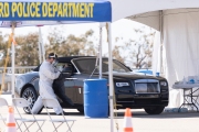 A health care worker tests a woman in a Rolls-Royce car  for COVID-19 at a testing drive-through center in Hayward, CA, on April 15, 2020.  Hayward firefighters with cooperation with Hayward Police and paramedics set up the center to take pressure off hospital emergency rooms. It is free and available to anyone who show symptoms such as fever.