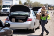 A volunteer loads bags of food into the trunk of car  at the Alameda Food Bank distribution center in Alameda, CA, on April 15, 2019. The food was distributed  through a drive-through to people in need following the loss of their jobs due to the “shelter-in-place” order to limit the spread of the coronavirus SARS-CoV-2.