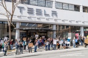 Demonstrators gather outside the Tesla dealership in San Francisco, CA, on March 29, 2025, as part of the global "Tesla Takedown" protests. These protests, spanning over 200 locations worldwide, were organized to oppose Elon Musk's involvement with the U.S. federal government and the associated budget cuts and layoffs. The protesters held signs and chanted slogans to express their discontent with Musk's actions. The movement encourages individuals to boycott Tesla products and divest from Tesla stock, aiming to impact the company's financial standing as a form of protest.