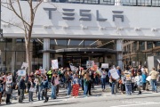 Demonstrators gather outside the Tesla dealership in San Francisco, CA, on March 29, 2025, as part of the global "Tesla Takedown" protests. These protests, spanning over 200 locations worldwide, were organized to oppose Elon Musk's involvement with the U.S. federal government and the associated budget cuts and layoffs. The protesters held signs and chanted slogans to express their discontent with Musk's actions. The movement encourages individuals to boycott Tesla products and divest from Tesla stock, aiming to impact the company's financial standing as a form of protest.