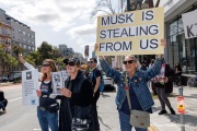 Demonstrators gather outside the Tesla dealership in San Francisco, CA, on March 29, 2025, as part of the global "Tesla Takedown" protests. These protests, spanning over 200 locations worldwide, were organized to oppose Elon Musk's involvement with the U.S. federal government and the associated budget cuts and layoffs. The protesters held signs and chanted slogans to express their discontent with Musk's actions. The movement encourages individuals to boycott Tesla products and divest from Tesla stock, aiming to impact the company's financial standing as a form of protest.