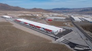 The Switch data center campus at the Tahoe Reno Industrial Center (TRIC), east of Sparks, NV, is one of the largest data center developments in the world and a defining symbol of the hyperscale infrastructure transforming northern Nevada into a major technology hub. Known for its massive, highly secure facilities, Switch built the campus to support cloud computing, enterprise data storage, and artificial intelligence workloads for large corporate clients. The company was drawn to TRIC by Nevada’s favorable tax structure, available land, access to renewable energy, and fast fiber connections to the Bay Area. The campus also uses an advanced cooling system designed for the desert climate, relying heavily on outside air and evaporative cooling technologies to reduce energy consumption while maintaining stable temperatures for thousands of servers operating around the clock. Surrounded by desert landscapes and heavy industrial development, the sprawling campus reflects the enormous physical footprint and energy demands of the digital economy powering modern internet and AI services.